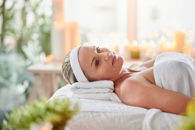 Une masseuse professionnelle place délicatement des pierres noires chaudes sur le dos nu d'une femme allongée sur le ventre pour un massage relaxant.